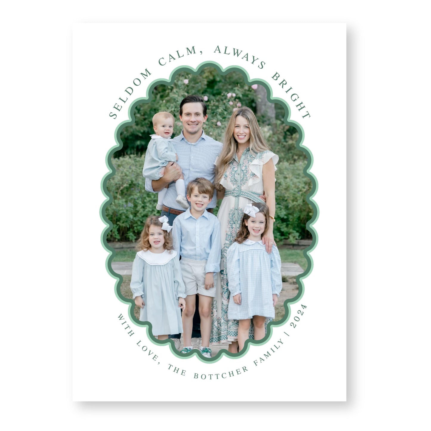 A family portrait of a man, woman, and three children, all dressed in light blue clothing, standing together in a garden setting.