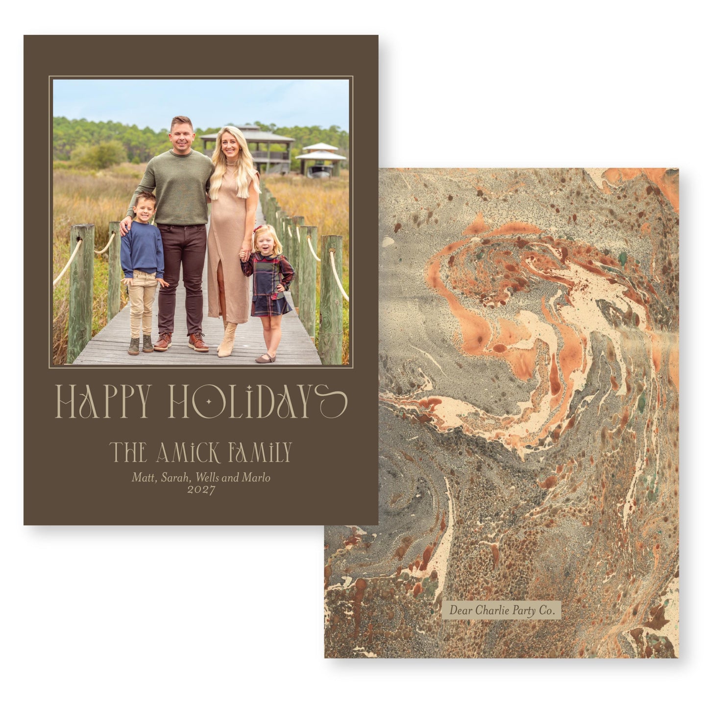 The image is a holiday card featuring a family of four, including a man, a woman, and two children, standing on a wooden boardwalk. The card has a marbled background and a text that reads "Happy Holiday! The A.Mick Family Matt, Sarah, Will and Marlo 2027".
