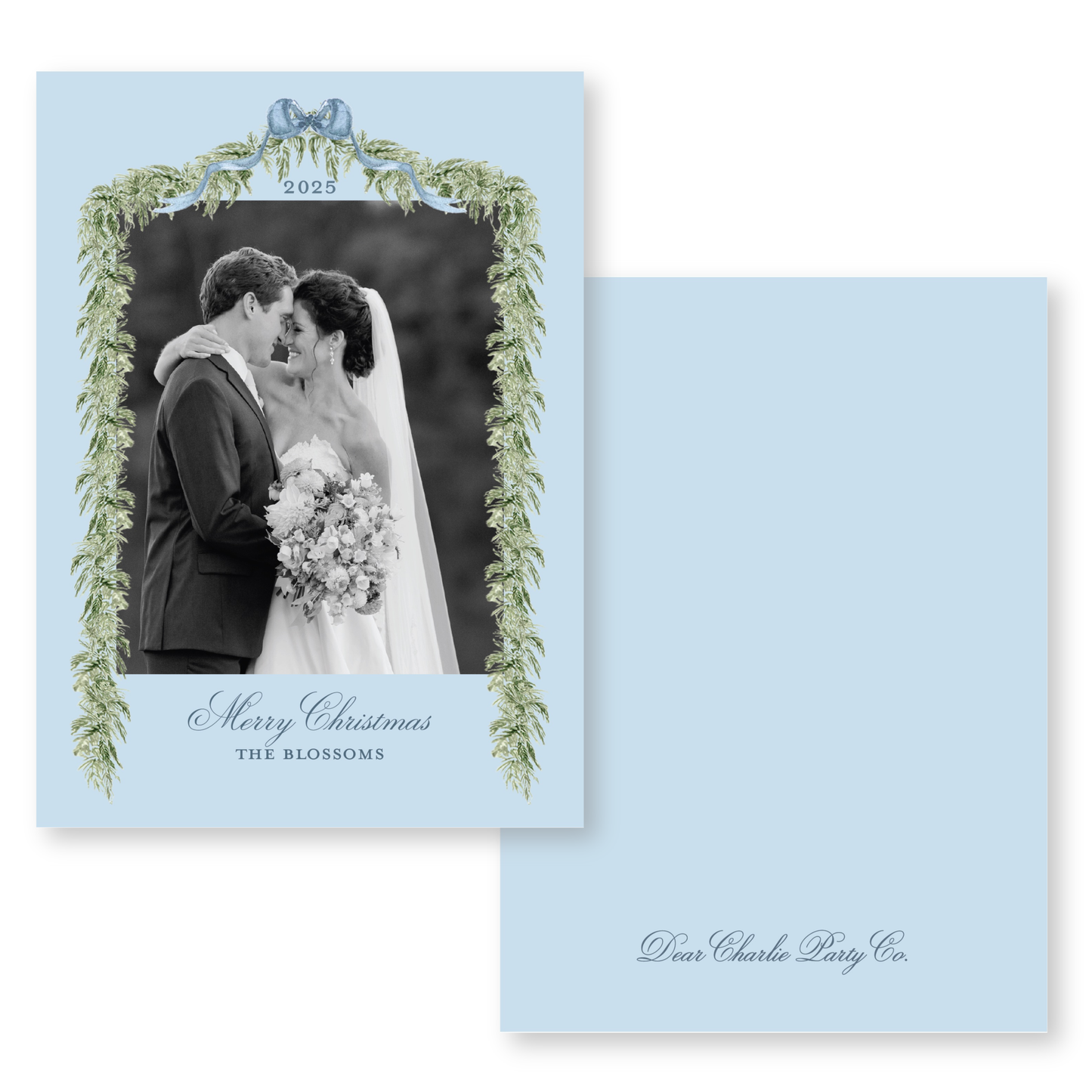 A black and white photo of a bride and groom embracing, framed by a decorative border of greenery and the text "Merry Christmas THE BLOSSOMS".