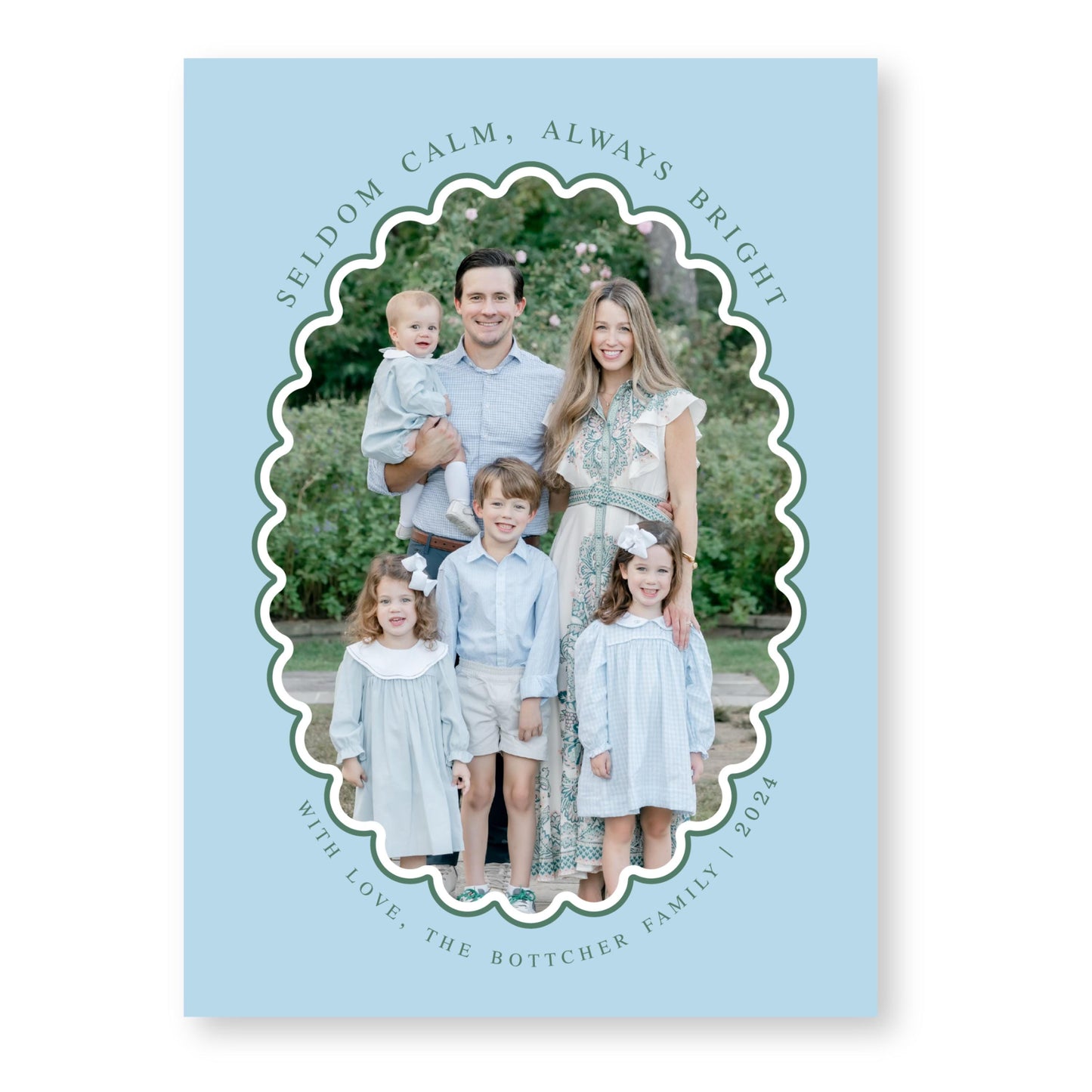 A family portrait of a man, woman, and three children, all dressed in light blue clothing, standing together in a garden setting.