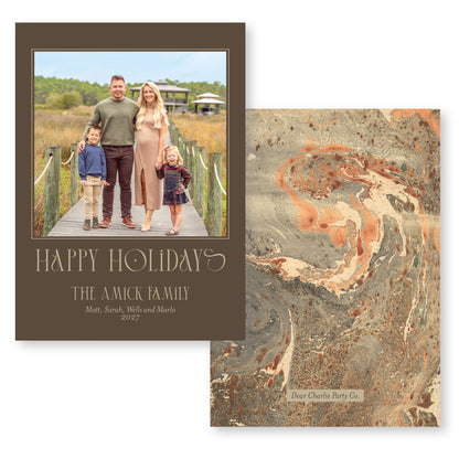 The image is a holiday card featuring a family of four, including a man, a woman, and two children, standing on a wooden boardwalk. The card has a marbled background and a text that reads &quot;Happy Holiday! The A.Mick Family Matt, Sarah, Will and Marlo 2027&quot;.