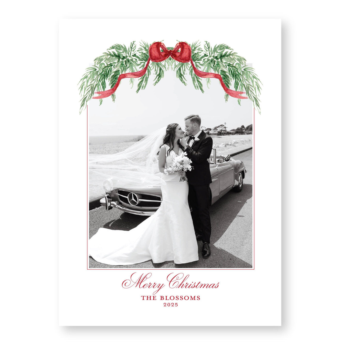 A black and white photograph of a bride and groom standing next to a car, with a festive wreath of greenery and a red ribbon above them. The text at the bottom of the image reads "Merry Christmas THE BLOSSOMS 2020".
