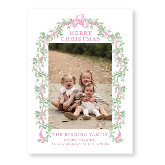 three young children sitting together on a path, surrounded by a decorative border with pink and green leaves. The text "Merry Christmas" is displayed above the children, and "THE BINNING FAMILY" is written below them.