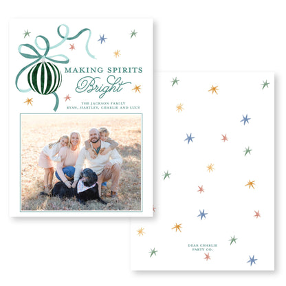 The image is a holiday card featuring a family photo of a man, woman, and two children posing together in a field. The card has a festive design with stars and a ribbon, and the text &quot;Making Spirits Bright&quot; and &quot;The Jackson Family&quot; is displayed.