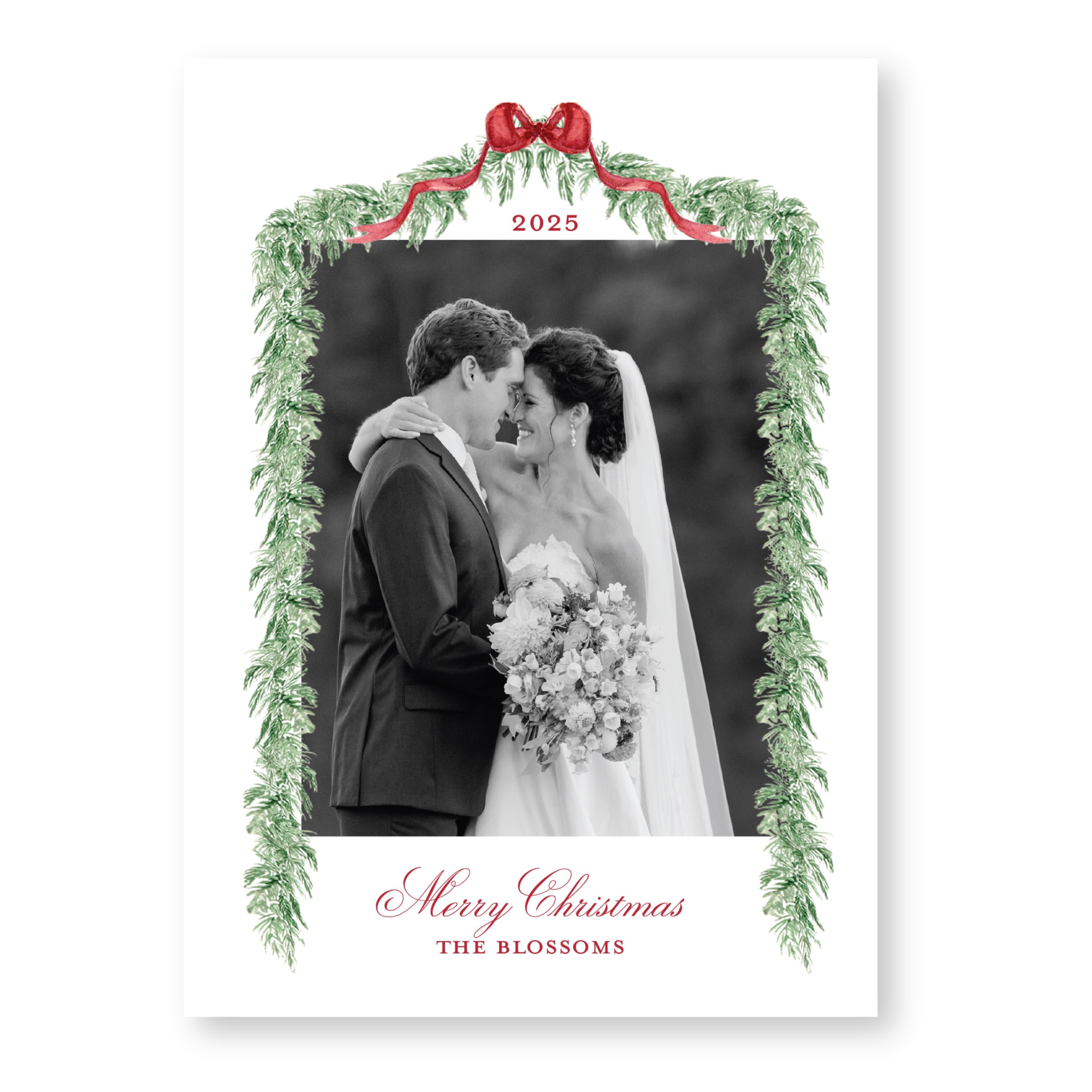 A black and white photograph of a couple embracing, with a festive wreath frame around the image. The text "Merry Christmas" and "THE BLOSSOMS" is displayed below the frame.