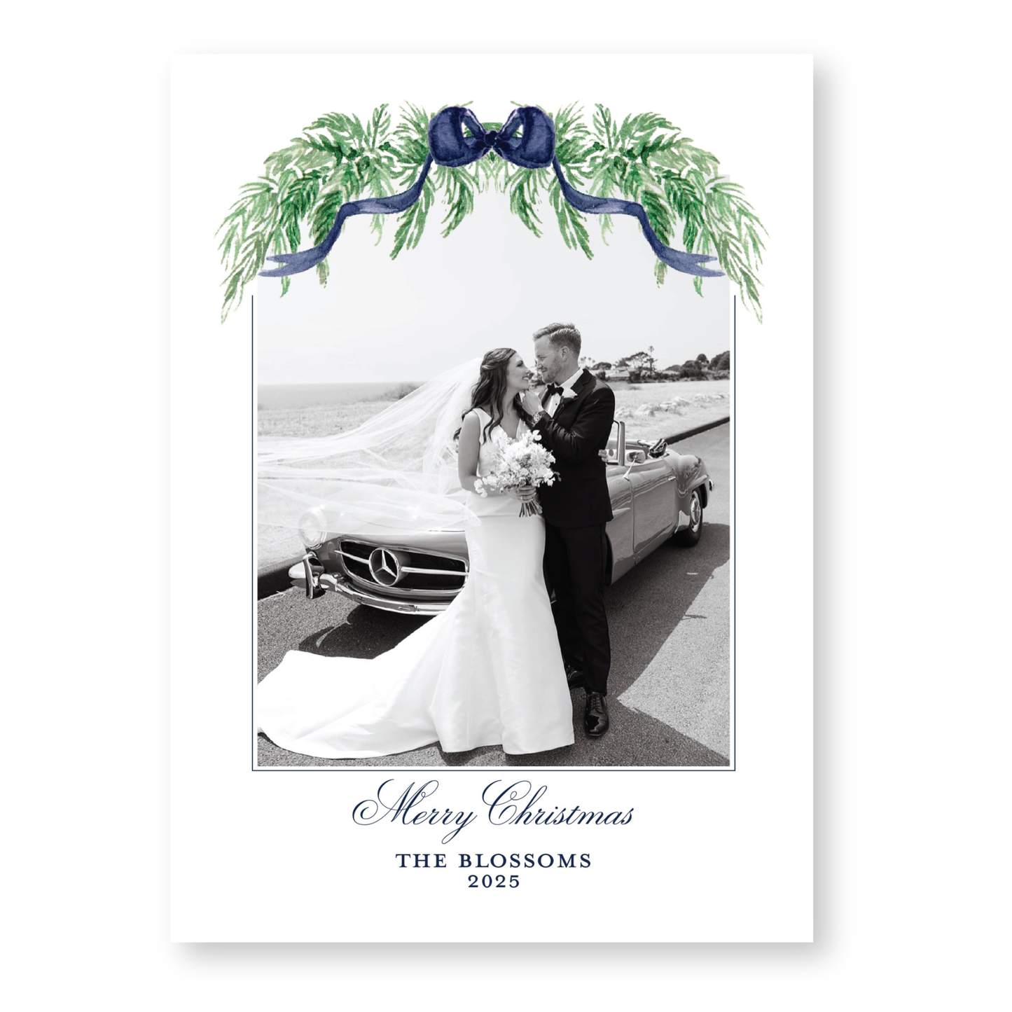 A black and white photograph of a bride and groom standing next to a car, with a festive wreath and ribbon decoration above them. The text at the bottom of the image reads "Merry Christmas THE BLOSSOMS 2015".