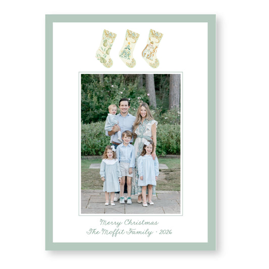 A family portrait of a man, woman, and three children dressed in matching light blue outfits, standing together in a garden setting.