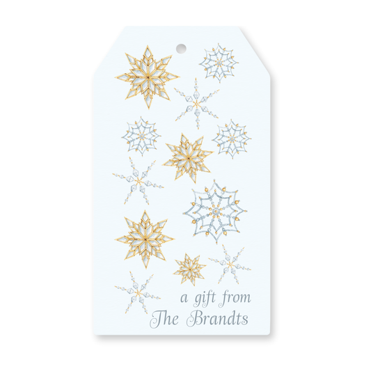 a white gift tag with gold and silver snowflakes