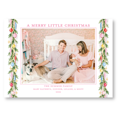 A family photo of a couple and their newborn baby, with a dog in the background, is framed with a Christmas tree decoration border.