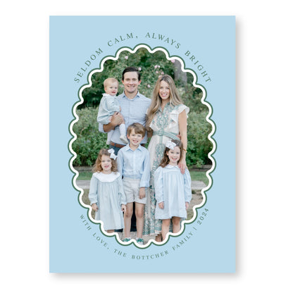 A family portrait of a man, woman, and three children, all dressed in light blue clothing, standing together in a garden setting.