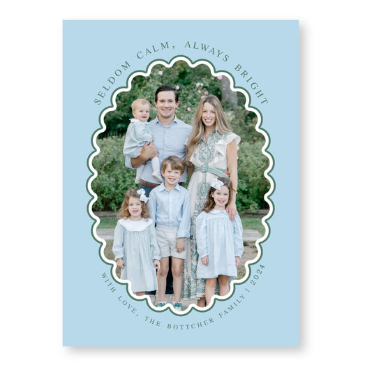 A family portrait of a man, woman, and three children, all dressed in light blue clothing, standing together in a garden setting.
